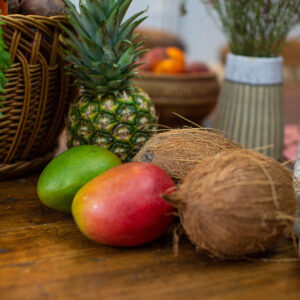Fresh tropical fruits, including mangoes, coconuts, and pineapple, arranged on a rustic wooden table, symbolising a fresh, whole-food approach to personalised nutrition